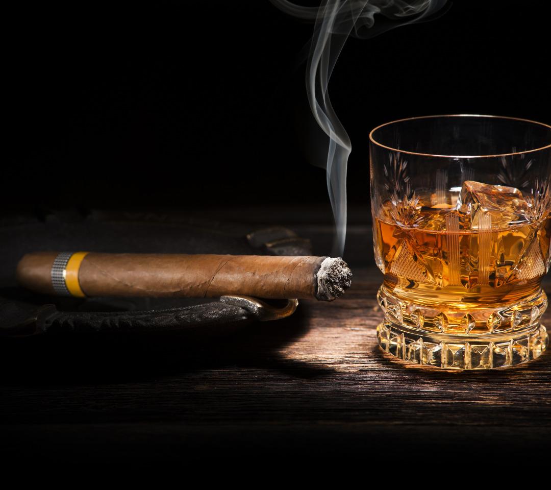 An open branded humidor of premium cigars with a whiskey pour